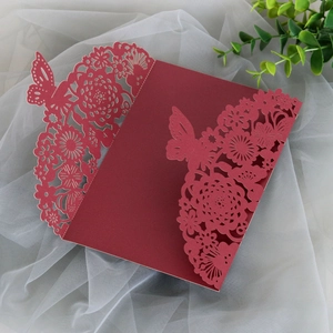 Macro shot of burgundy laser-cut wedding card featuring floral and butterfly patterns