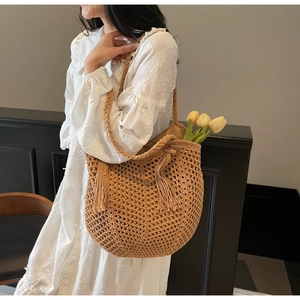 Détail d'un sac cabas en paille tissé à la main avec pompons et larges anses