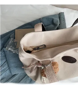 Gros plan d'une fermeture éclair en métal marron et d'un logo sur un sac cabas en toile