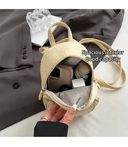 Détail de l'intérieur du mini sac à dos montrant le cuir litchi et l'espace de rangement