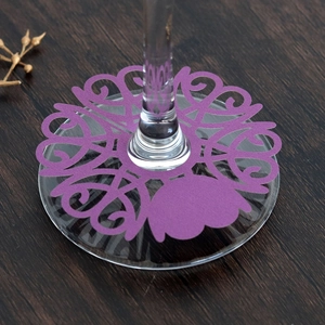 Detail of laser-cut purple hollow wine glass place card with heart and flower patterns