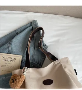 Détail du sac fourre-tout en toile beige avec sangles brunes et pendentif ours