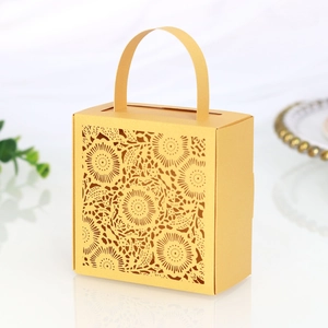 Detail of laser-cut sunflower pattern on golden wedding favor gift box with handle