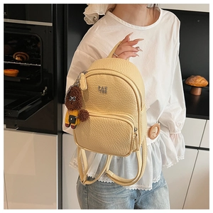 Détail du sac à dos en cuir jaune clair avec un charmant porte-clés ours en peluche