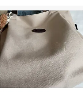 Gros plan sur le matériau du sac cabas en toile beige avec un porte-clé ours en peluche