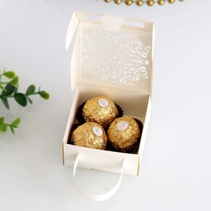 Detail of laser-cut lace pattern on ivory wedding candy box with elegant handle