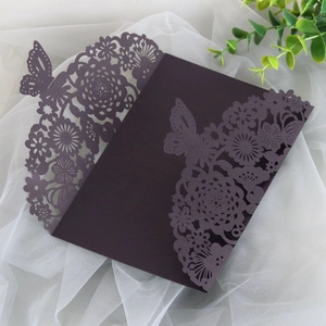 Detailed laser-cut dark purple invitation card featuring intricate butterfly and floral patterns