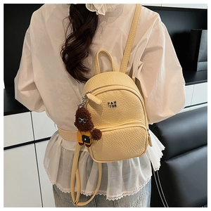 Mini sac à dos jaune en cuir avec breloque chien porté par un mannequin de dos