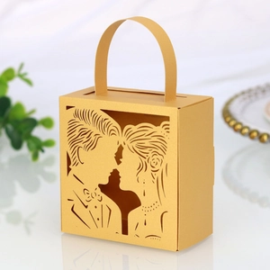 Λεπτομέρεια χρυσού κουτιού γλυκών laser-cut με σιλουέτα νύφης και γαμπρού και λάμψη