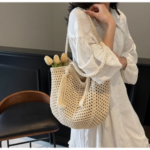 Detail of hollow woven shoulder bag with long tassel charms and straw textures