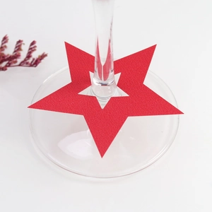 Detalle de tarjeta roja en forma de estrella para copas de vino en decoración de mesa