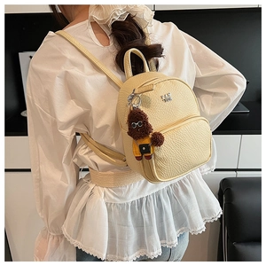 Vue arrière d'un mini sac à dos en cuir crème avec pendentif chien mignon sur un mannequin