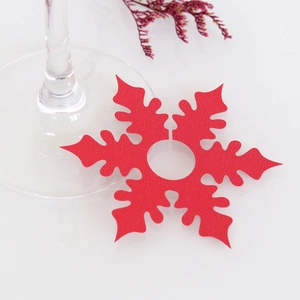 Macro shot of red snowflake wine glass place cards with textured paper and center hole