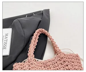 Detailaufnahme der rosa geflochtenen Handtasche mit Fokus auf Griff und Webstruktur
