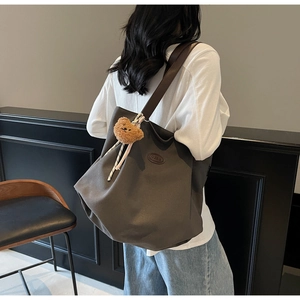 Détail d'un grand sac cabas avec bandoulière en cuir et pendentif en forme d'ourson