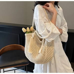 Détail du sac de plage tressé à la main crème avec pompons et bandoulière en maille