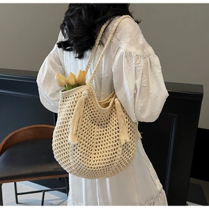 Detail of beige crochet tote bag featuring hollow knit patterns and long decorative tassels