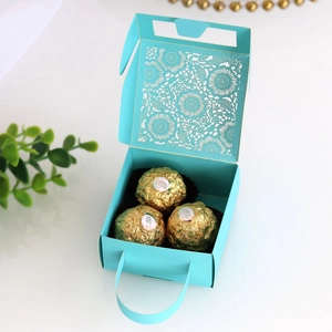 Detailed macro shot of laser-cut teal wedding favor box with gold foil chocolates