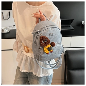 Détail du mini sac à dos bleu clair avec texture cuir grainé et breloque chien mignon