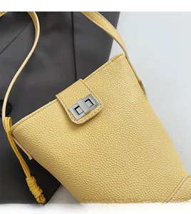 Close-up of yellow pebbled leather bucket bag with silver metal twist lock and strap