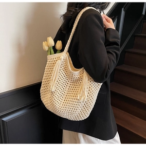Détail d'un sac cabas beige tissé à la main avec motifs en résille et longs glands latéraux