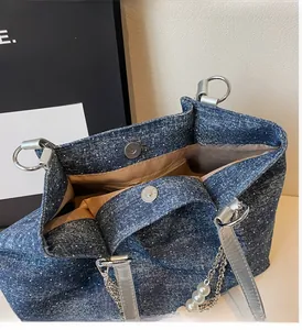Detail der Denim-Tasche mit Silberglitzer, Magnetverschluss und Perlenketten-Anhänger am Griff