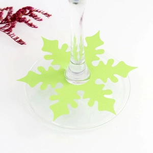 Detail of green snowflake wine glass place card on a transparent stemware base
