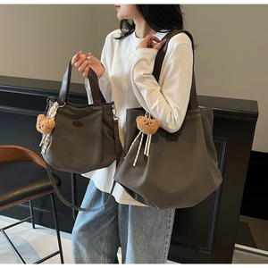 Détail du sac cabas en toile marron foncé et sac bandoulière avec pendentif ours et anses cuir