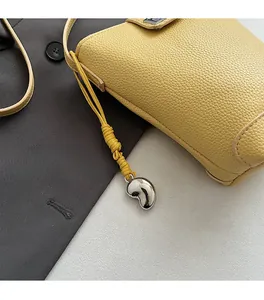 Close-up of yellow pebble leather bucket bag featuring a stylish silver heart pendant detail