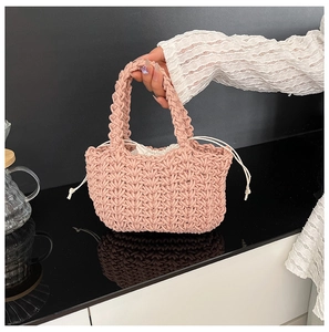 Close-up of pink hand-woven bucket bag featuring a cream drawstring liner and thick rope texture