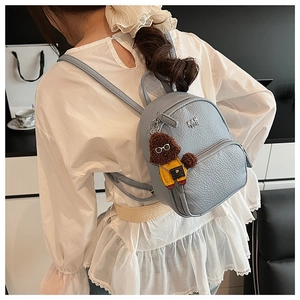 Détail d'un mini sac à dos bleu clair en cuir avec une peluche de chiot mignonne