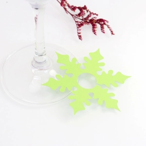 Close-up of a green snowflake-shaped wine glass card made of paper for festive table decor