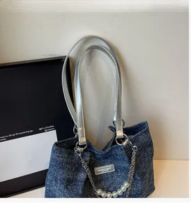 Detail einer dunkelblauen Denim-Tragetasche mit Perlen- und Metallkettenanhänger-Dekor