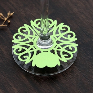 Close-up of laser-cut green vine wine glass place cards on a dark wooden table