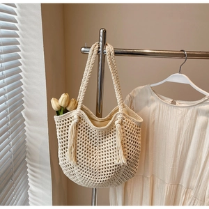 Détail du sac tressé en paille avec franges bohèmes et doublure sur un support métal