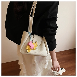 Detail of cream white leather bucket bag with pink elephant charm and brand logo