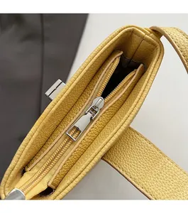 Close-up of smooth silver metal zipper and yellow pebble grain leather detail on bucket bag