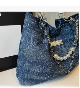 Detail der blauen Denim-Tragetasche mit silbernen Ketten und eleganter großer Perlenschnur