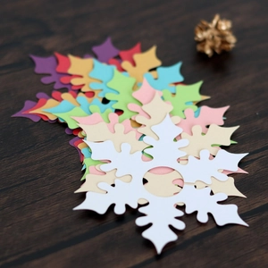 Detailed view of colorful snowflake place cards with intricate cutouts on wood surface