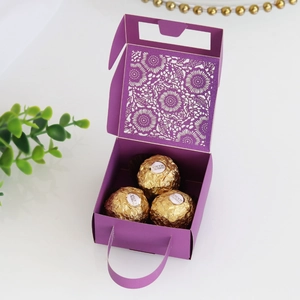 Detail of laser-cut purple candy box with floral patterns holding three chocolates