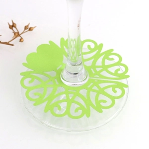 Close-up of light green laser-cut wedding place card for wine glass stems