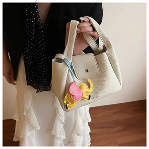 Close-up of beige lychee leather tote bag with a colorful leather elephant charm