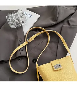 Detail of yellow lychee grain leather bucket bag with silver buckle on gray suit
