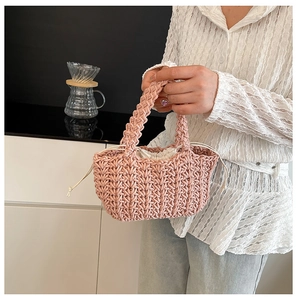 Borsa a mano in maglia rosa con fodera a coulisse tenuta da una donna in camicia bianca