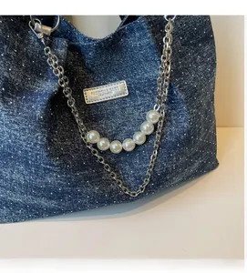 Detail der blauen Denim-Tasche mit weißen Punkten, Silberkette und großem Perlenhenkel