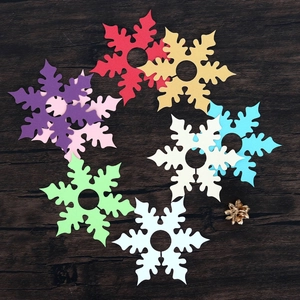 Detail of colorful paper snowflake wine glass cards on wood background with pine cone