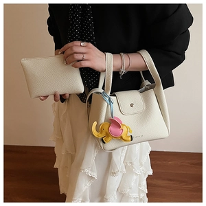 Close-up of white lychee leather bucket bag set with elephant charm and pouch