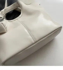 Close-up of beige faux leather bucket bag showing soft texture and fine stitching detail