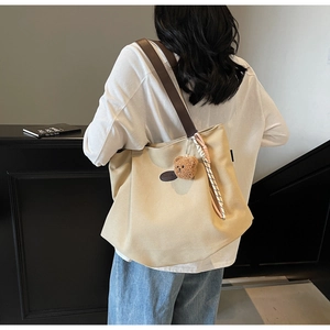 Détail du grand sac cabas en toile avec bandoulières en cuir et breloque ours mignon