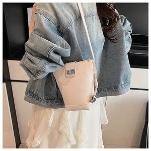 Close-up of beige lychee grain bucket bag featuring a silver twist lock and slim shoulder strap